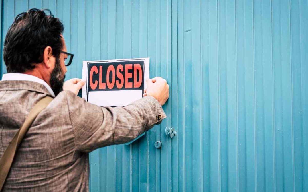 A person organizing finances on a desk with a calculator, a notebook, and a savings jar labeled 'Emergency Fund.'